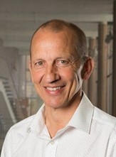 Mann in weißem Hemd steht in einem modern gestalteten Innenraum.